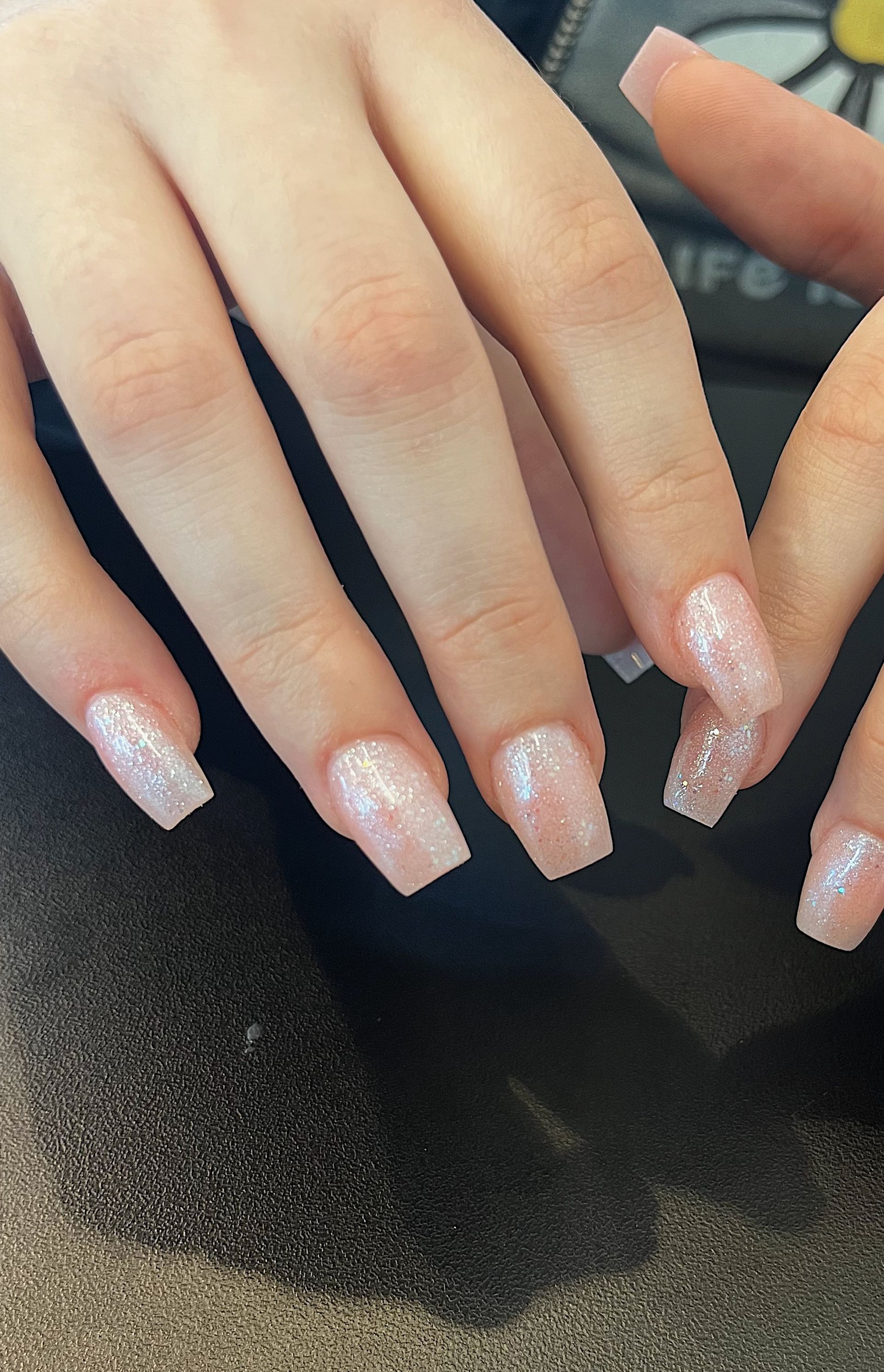 A close up of a woman 's nails with a daisy in the background