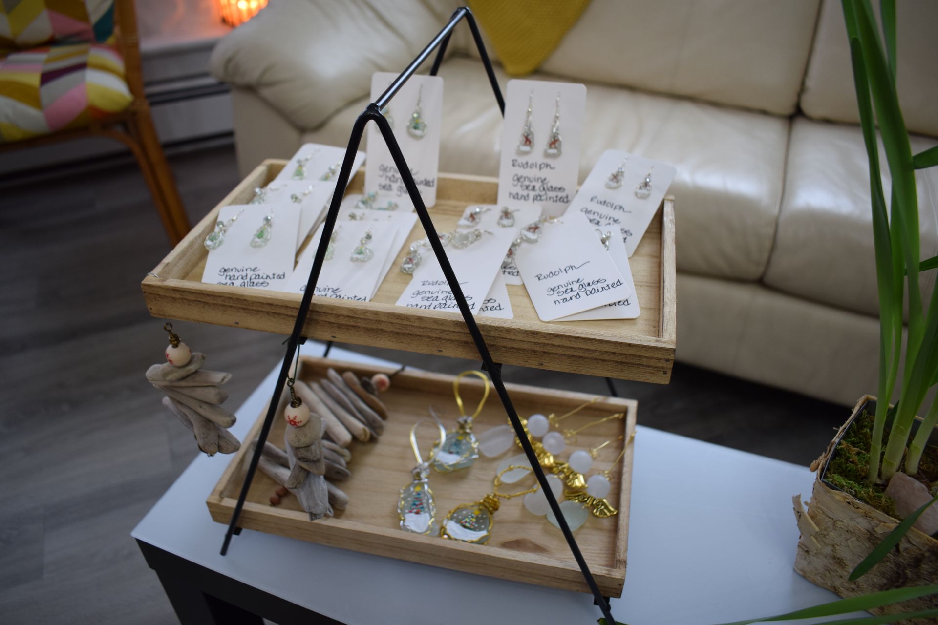 A wooden tray with earrings on it is on a table in a living room.