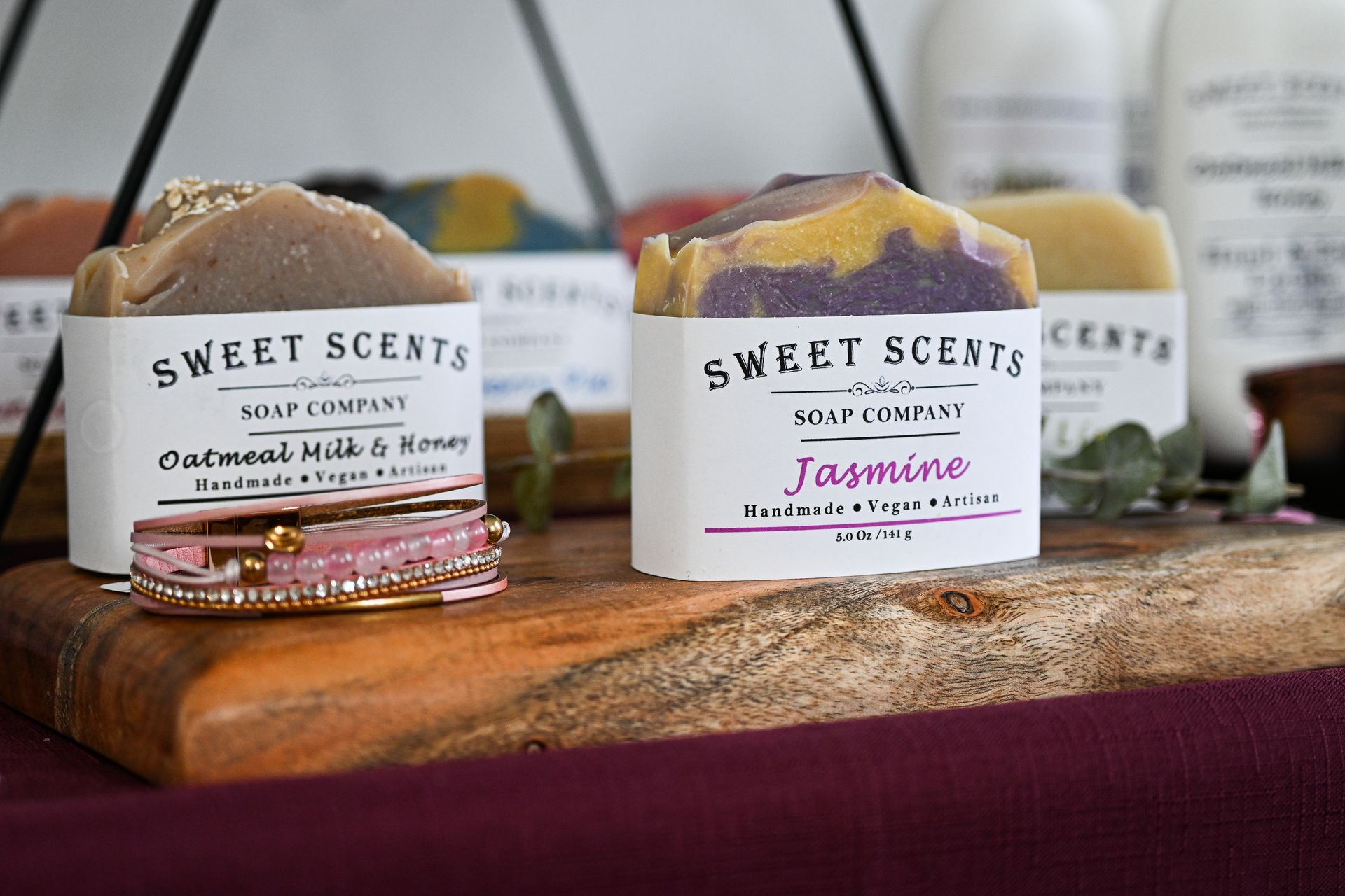 A wooden cutting board topped with soap bars from sweet scents soap company.