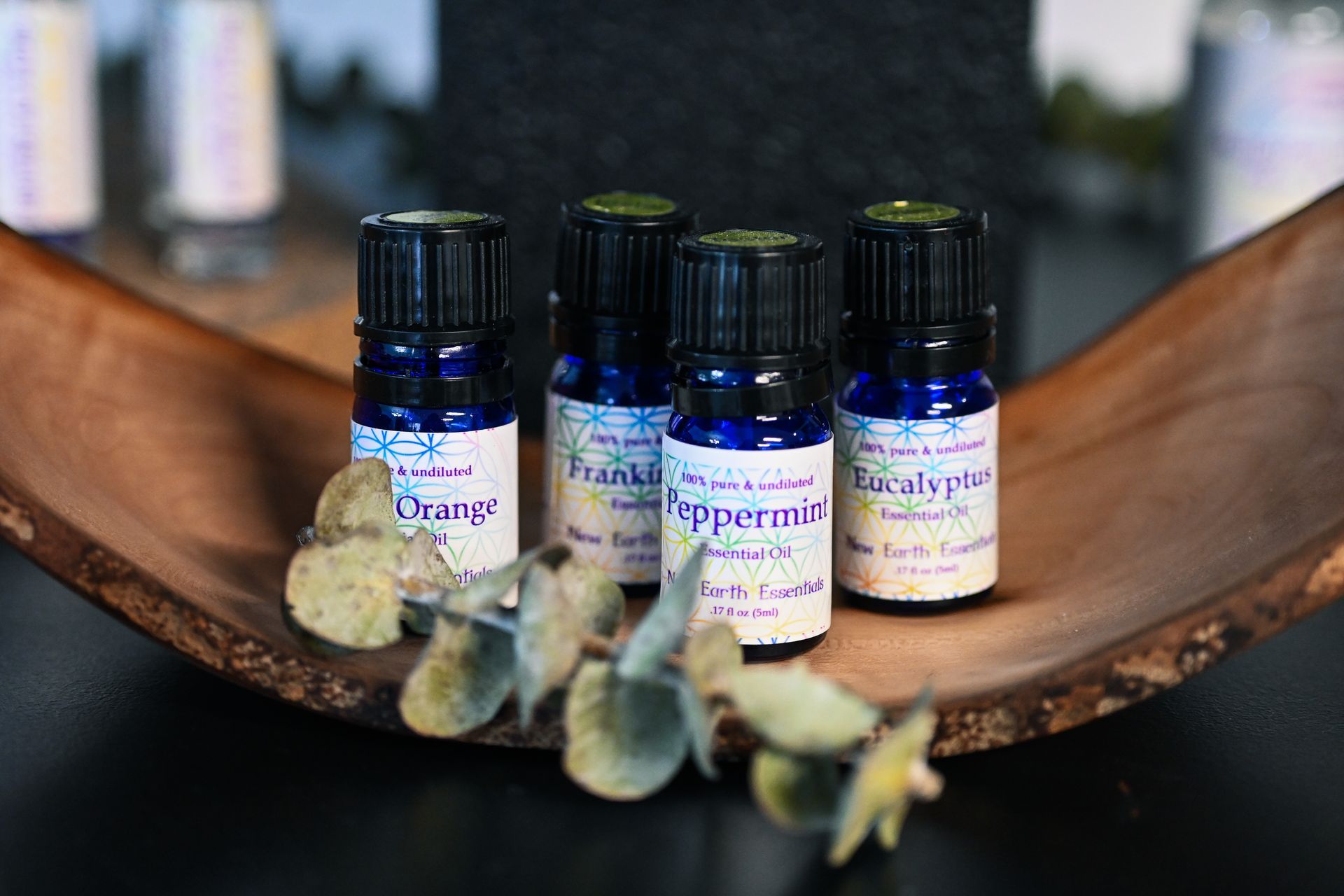 Five bottles of essential oils are sitting on a wooden tray.