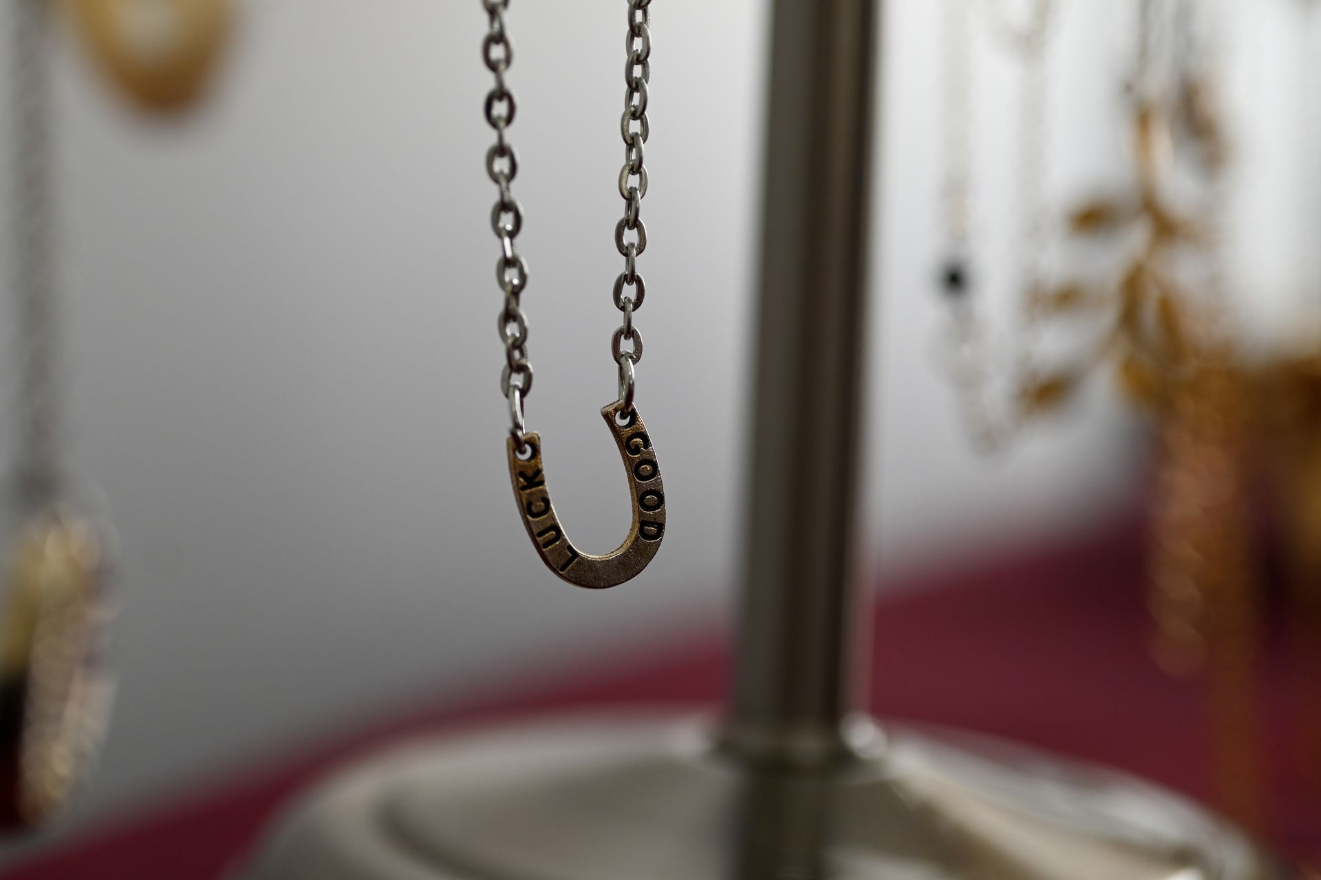 A horseshoe necklace is hanging from a chain on a stand