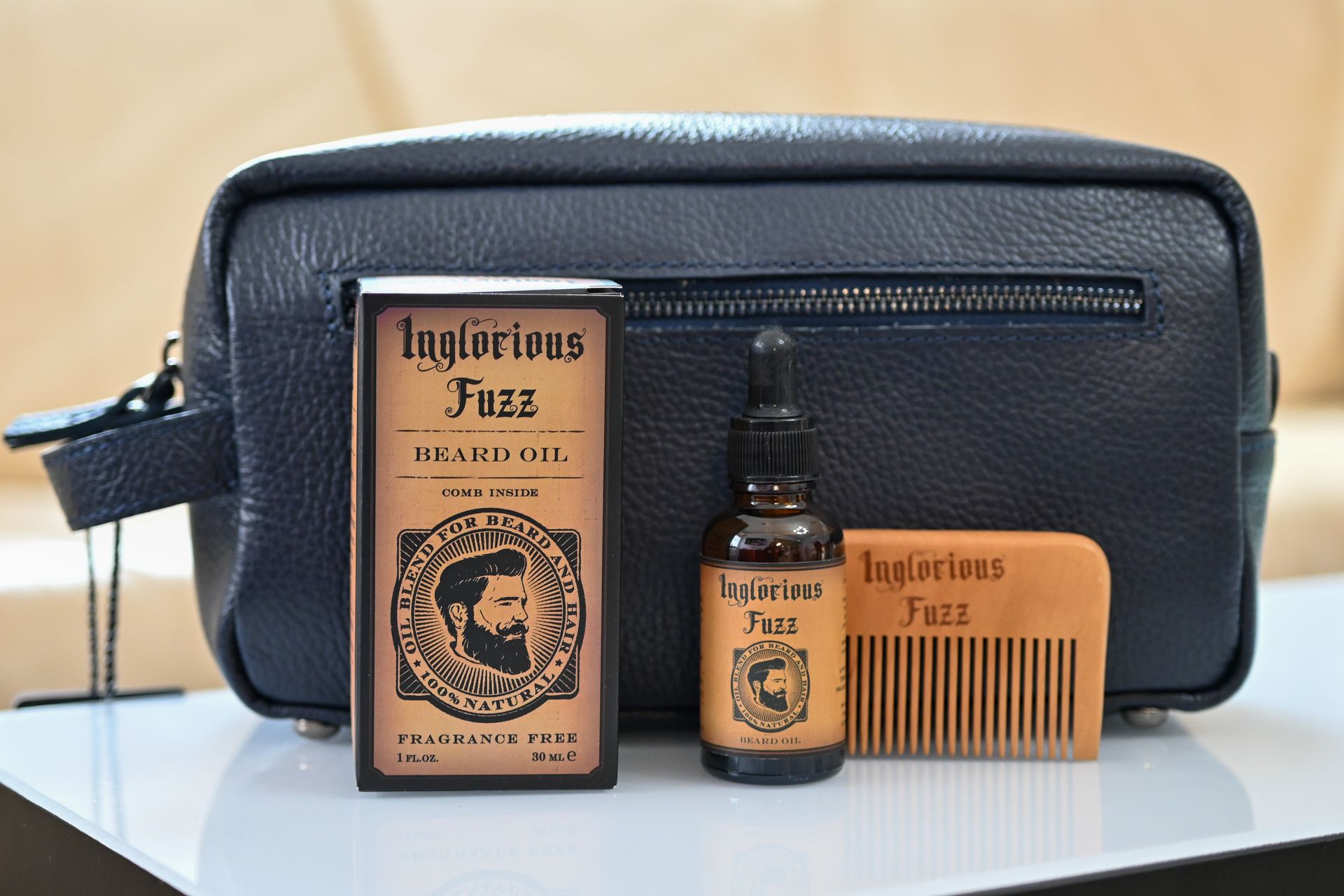 A black leather bag with a bottle of beard oil and a comb