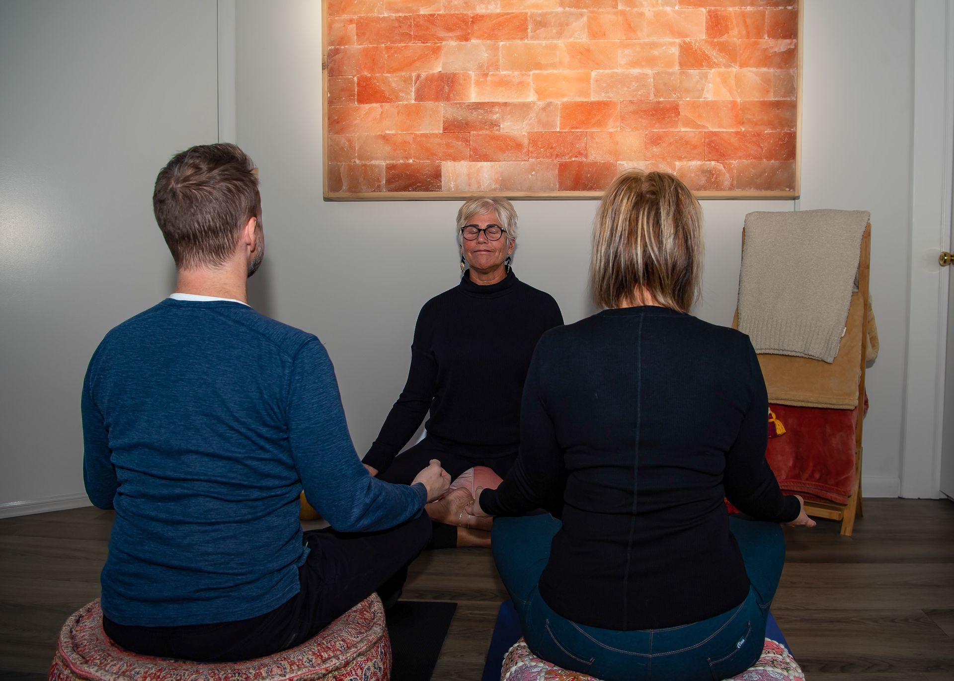 A group of people are sitting on the floor in a room holding hands.