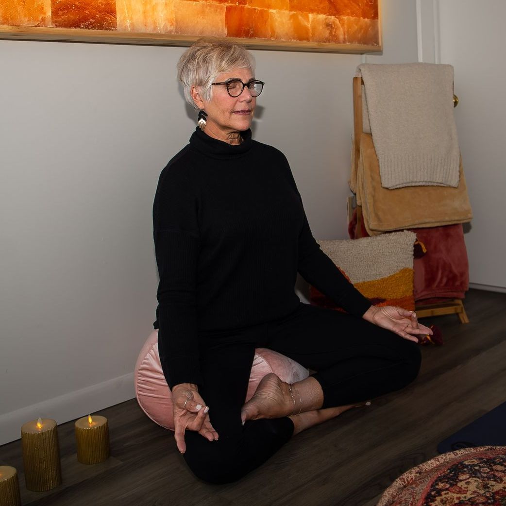 A woman is sitting on the floor in a lotus position.