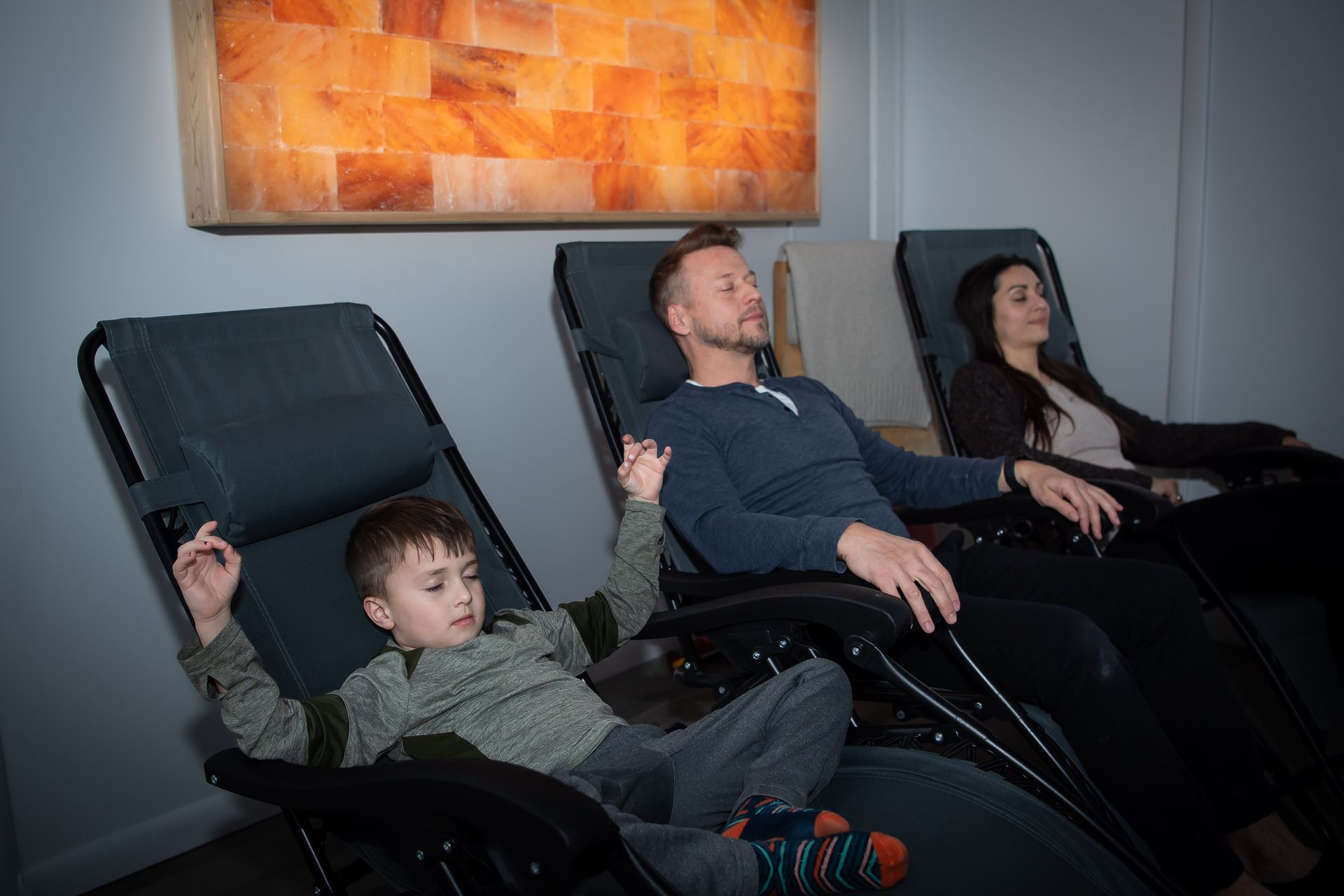 A man , woman and child are sitting in recliner chairs in a room.