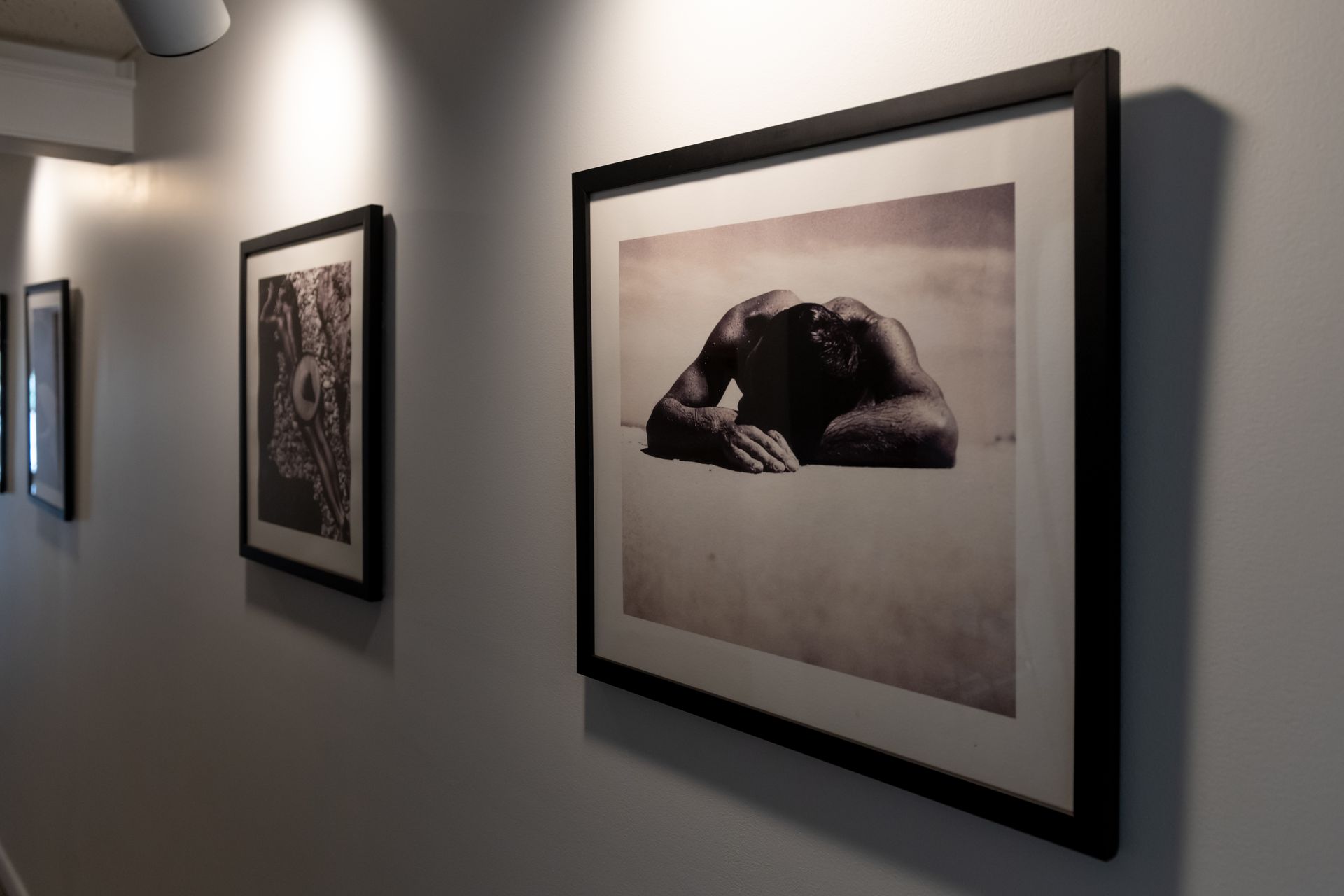 A row of framed pictures are hanging on a wall in a hallway.