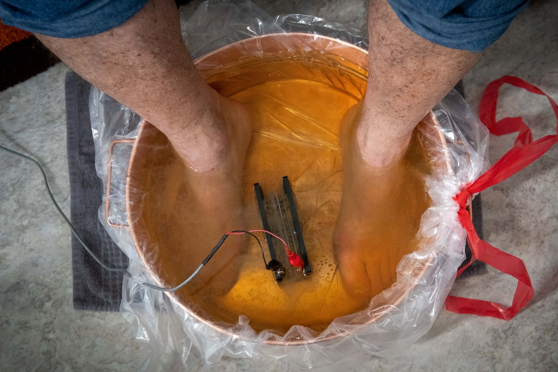 A person is sitting in a bowl of water with their feet in it.
