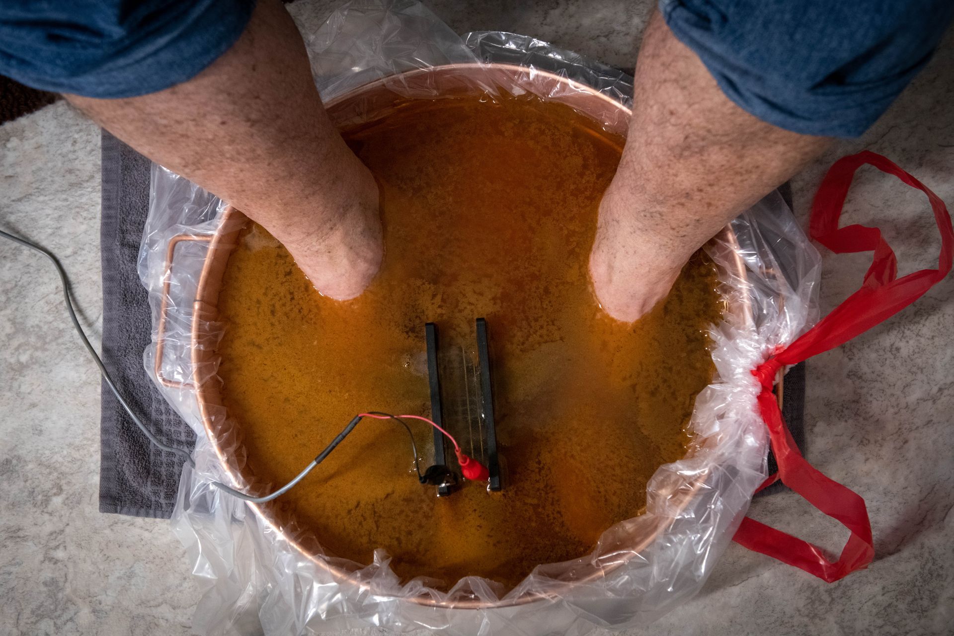 A person is sitting in a bowl of water with their feet in it.