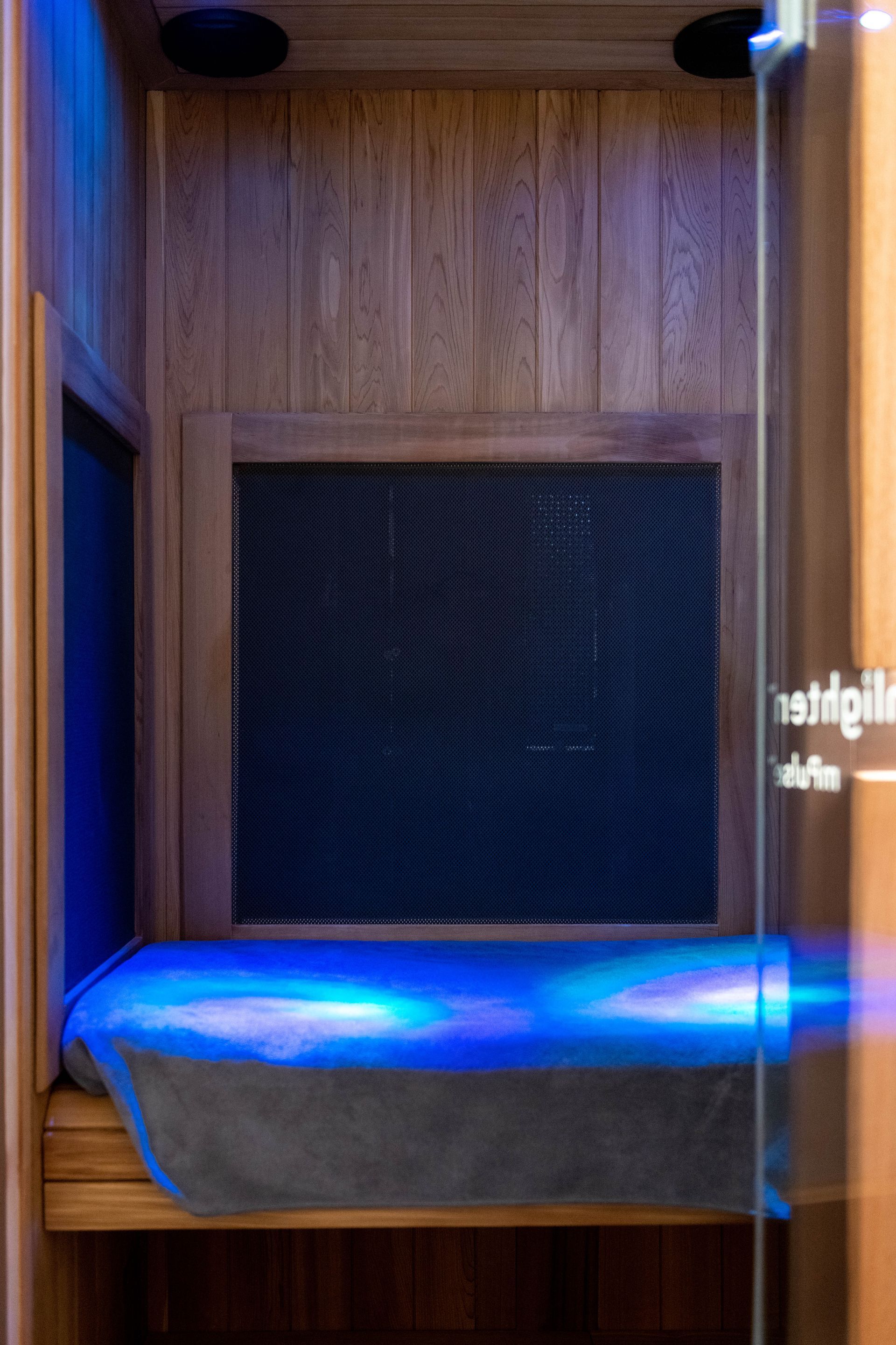 A sauna with a blue light coming out of the door.