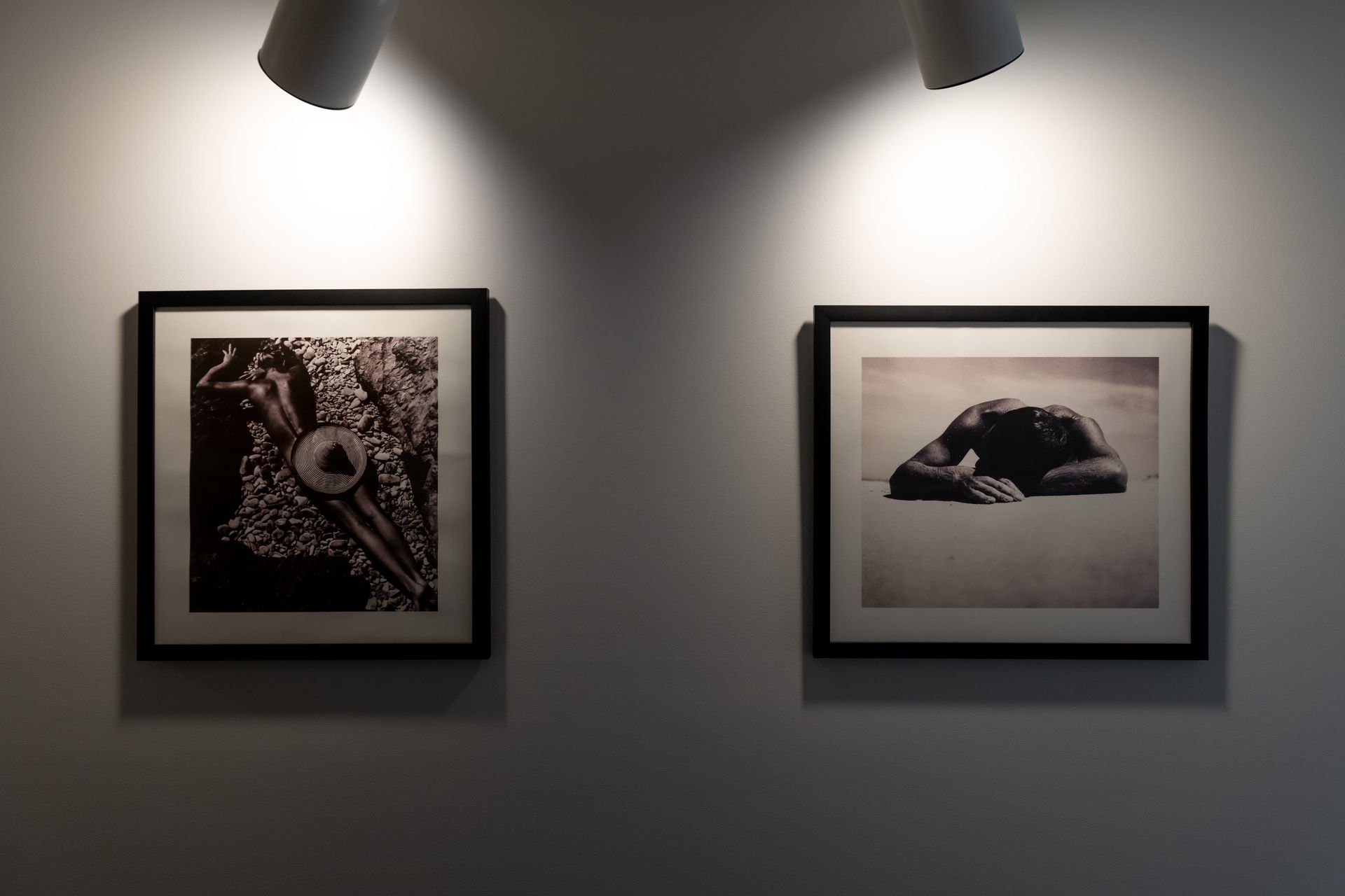 Two framed pictures are hanging on a wall under a light.