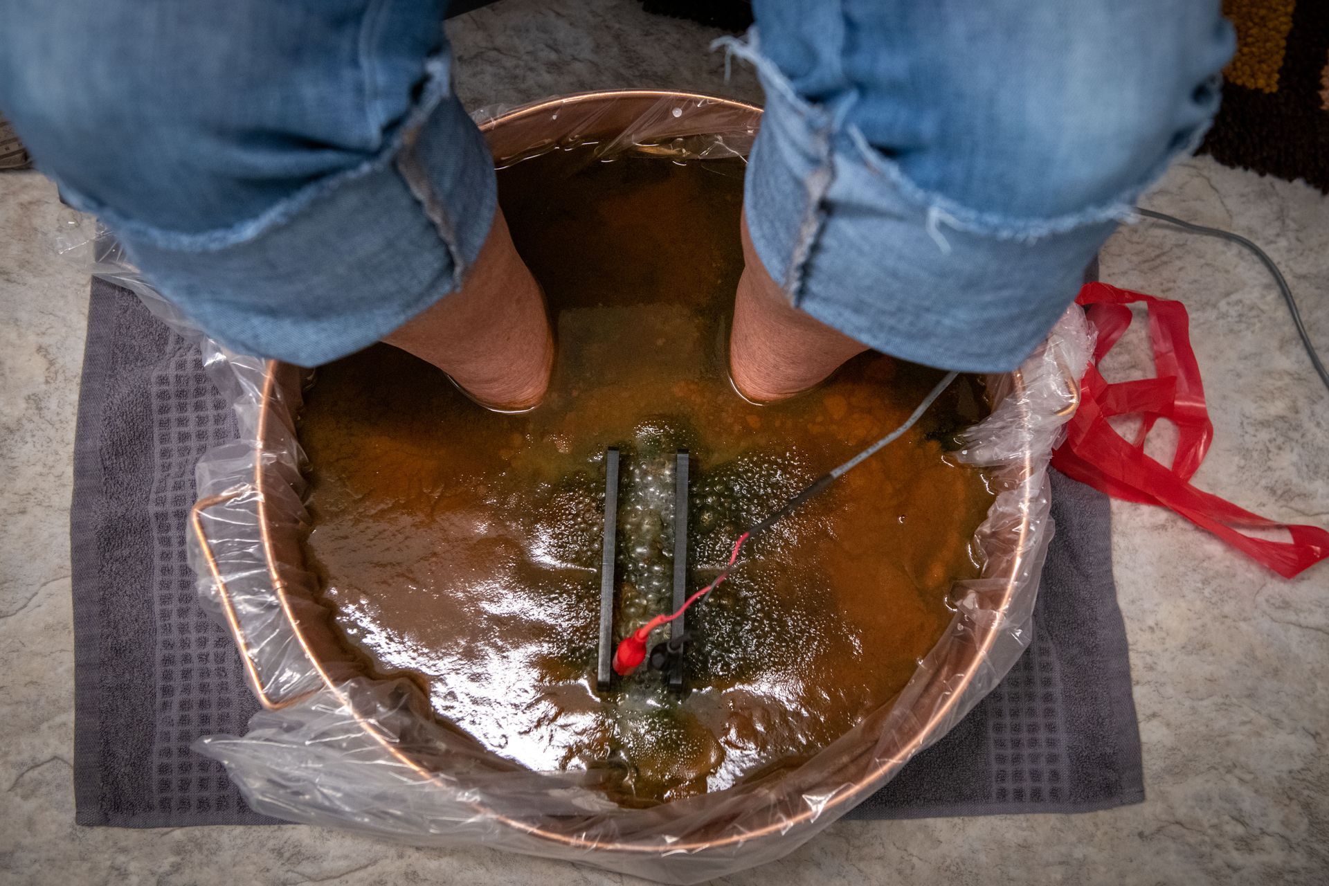 A person is sitting in a bowl of water with their feet in it.