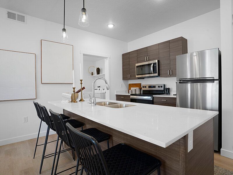 Modern kitchen with a large white island, stainless steel appliances, and dark wood cabinets.