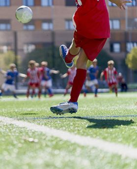 child in red uniform playing football
