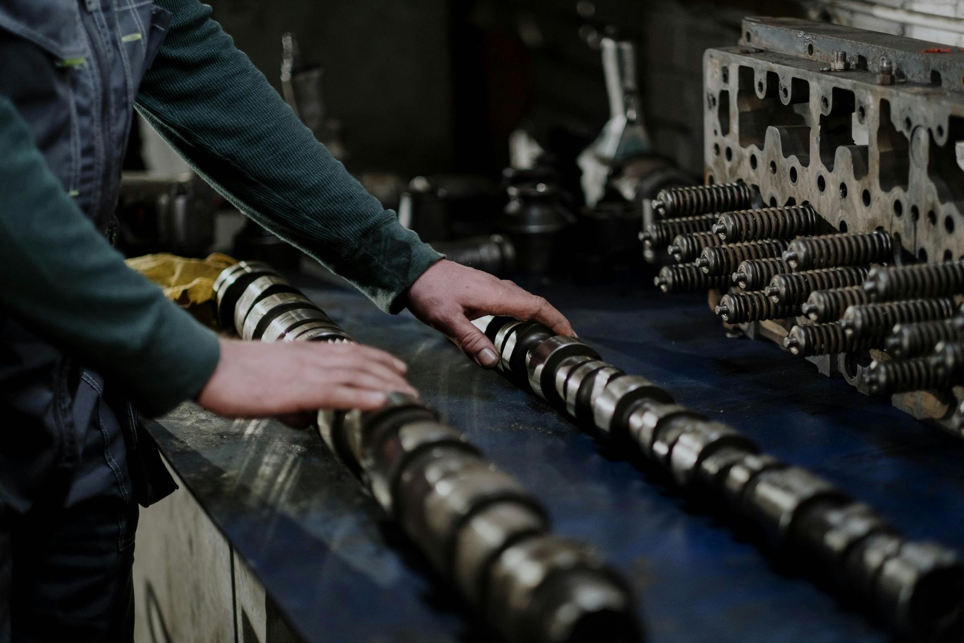 A man is working on a camshaft in a factory.