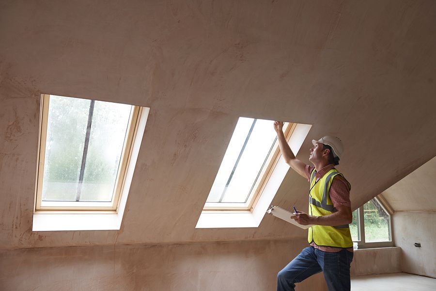 Worker installing skylight windows in an attic with sloped ceiling