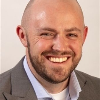 A man and a woman are sitting on a dock overlooking a lake.