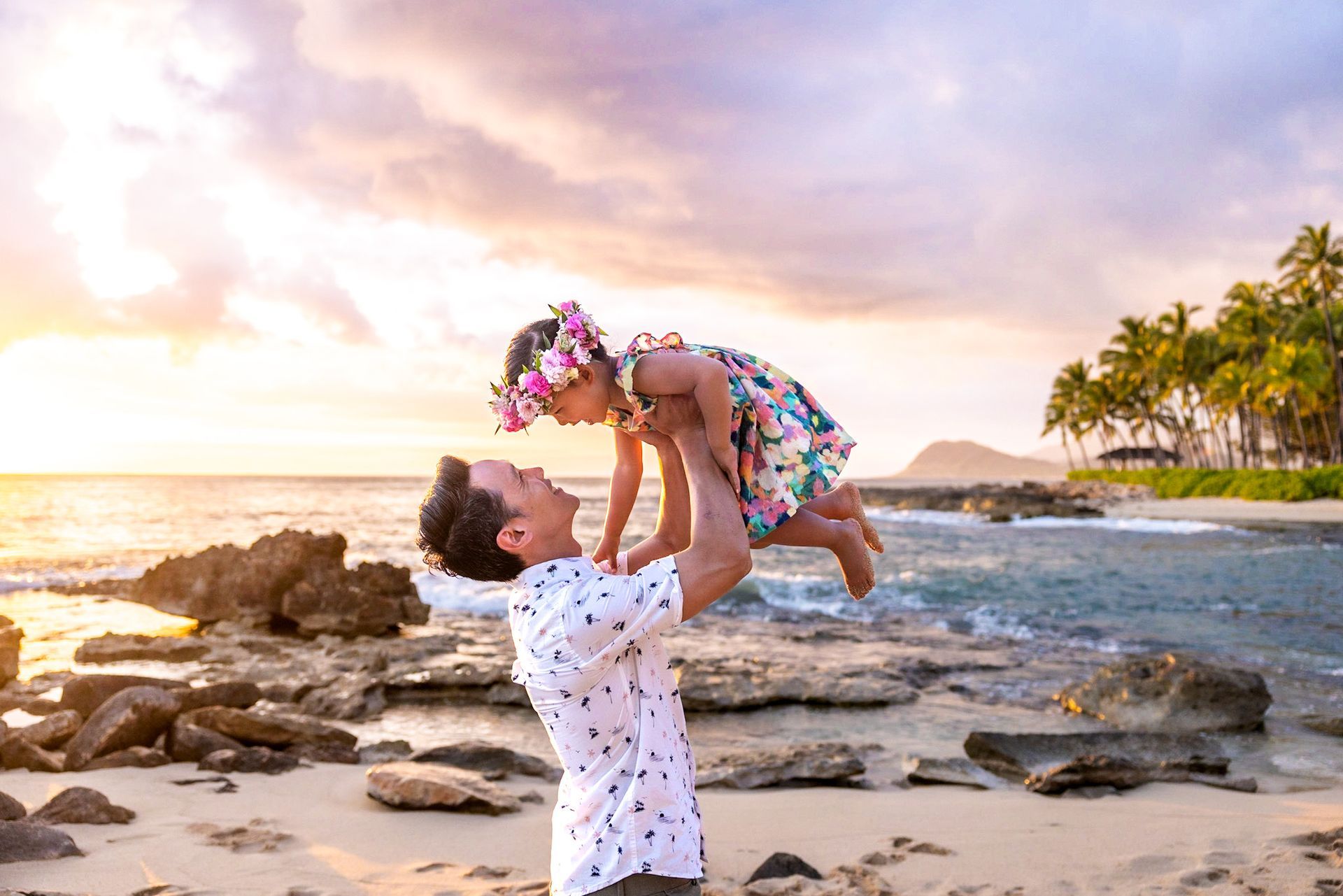 A man is holding a little girl in his arms on the beach.