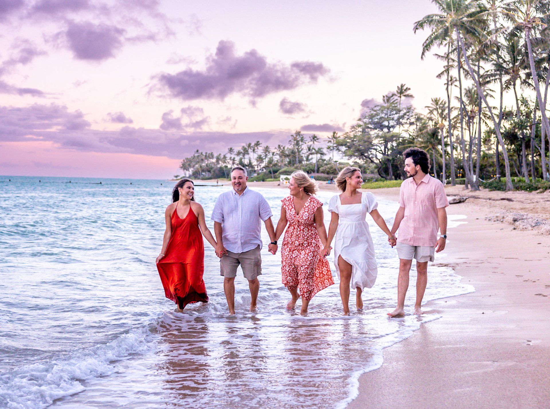 A family is walking on the beach holding hands.