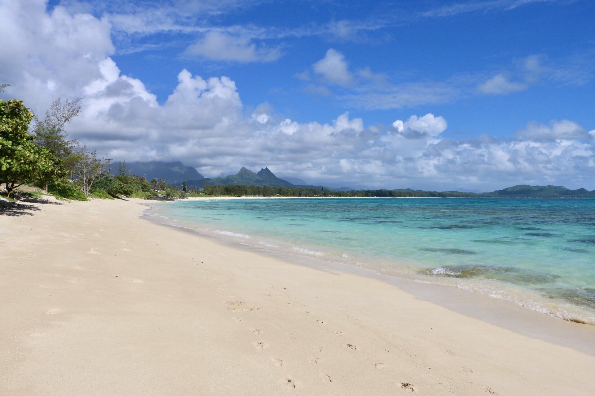 A beach with white sand and turquoise water on a sunny day.
