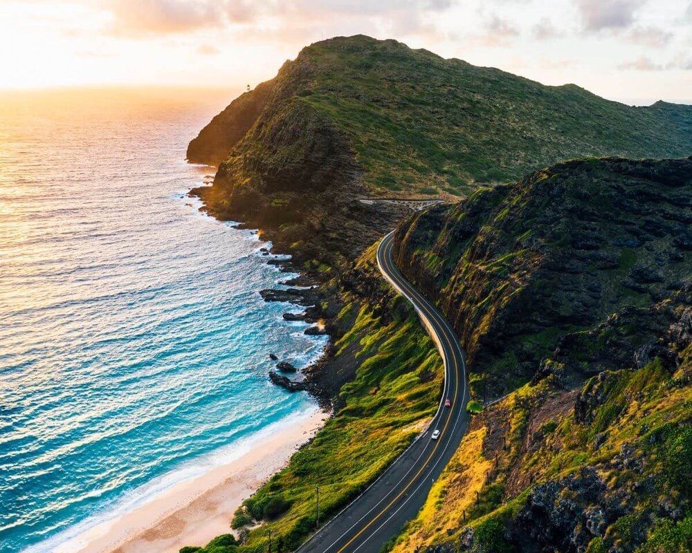 An aerial view of a road going through a cliff overlooking the ocean.
