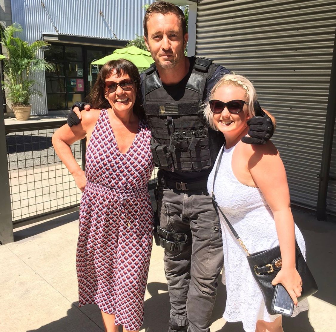 A man and two women are posing for a picture in front of a building.