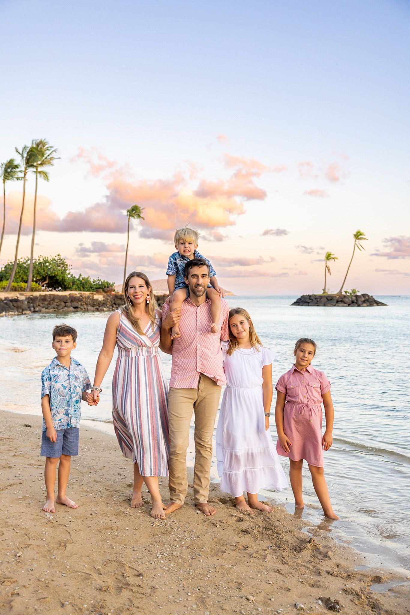 A family is posing for a picture on the beach.