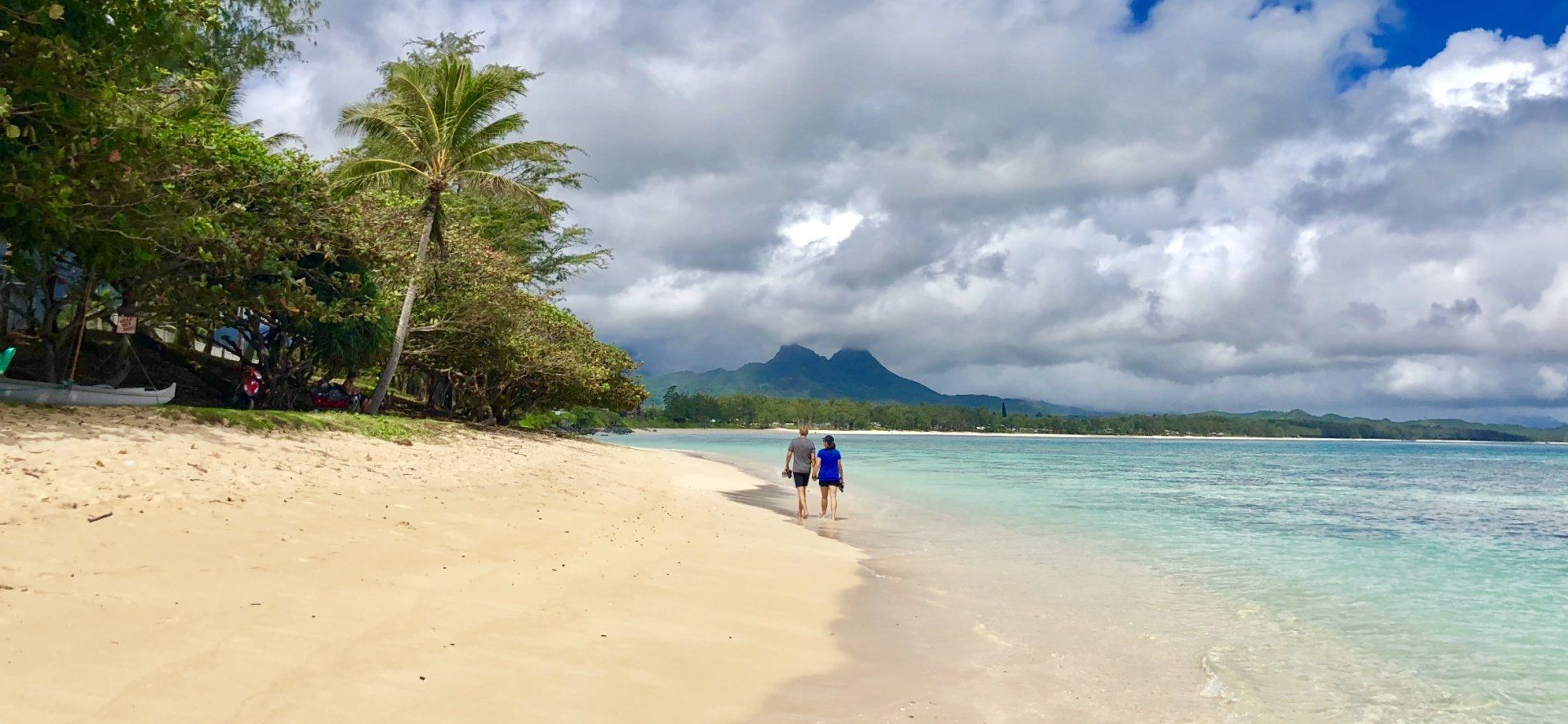 A couple is walking along a sandy beach near the ocean.