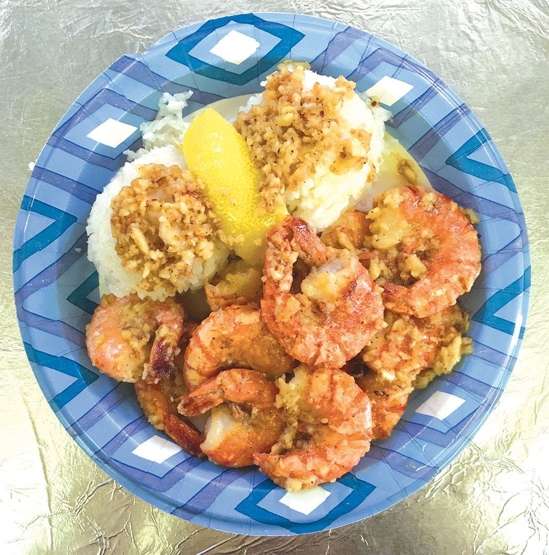 A plate of shrimp and mashed potatoes with a lemon wedge