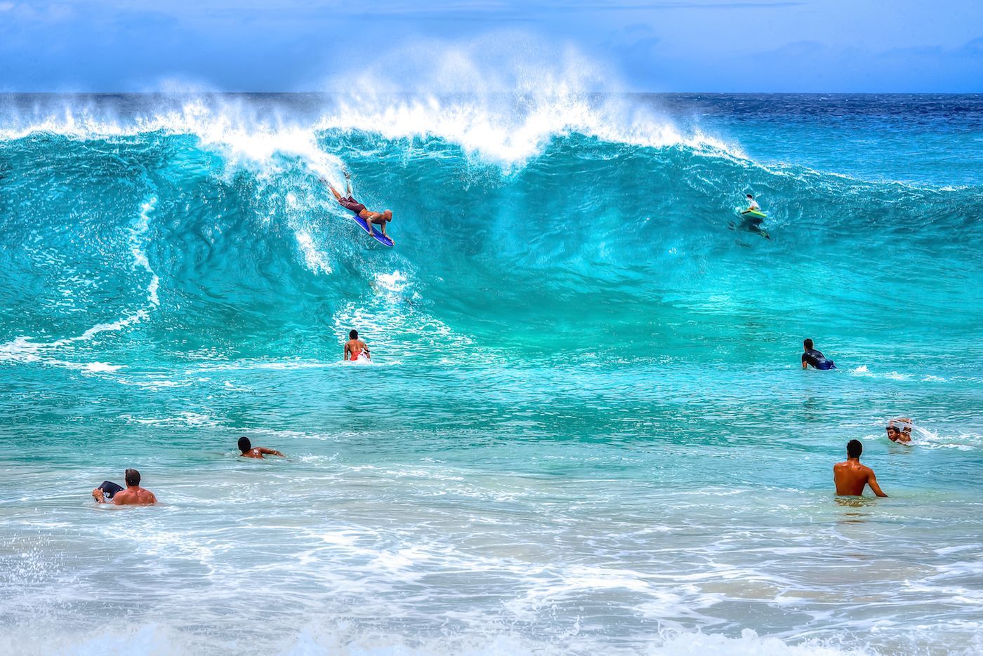 A group of people are surfing a wave on a beach.
