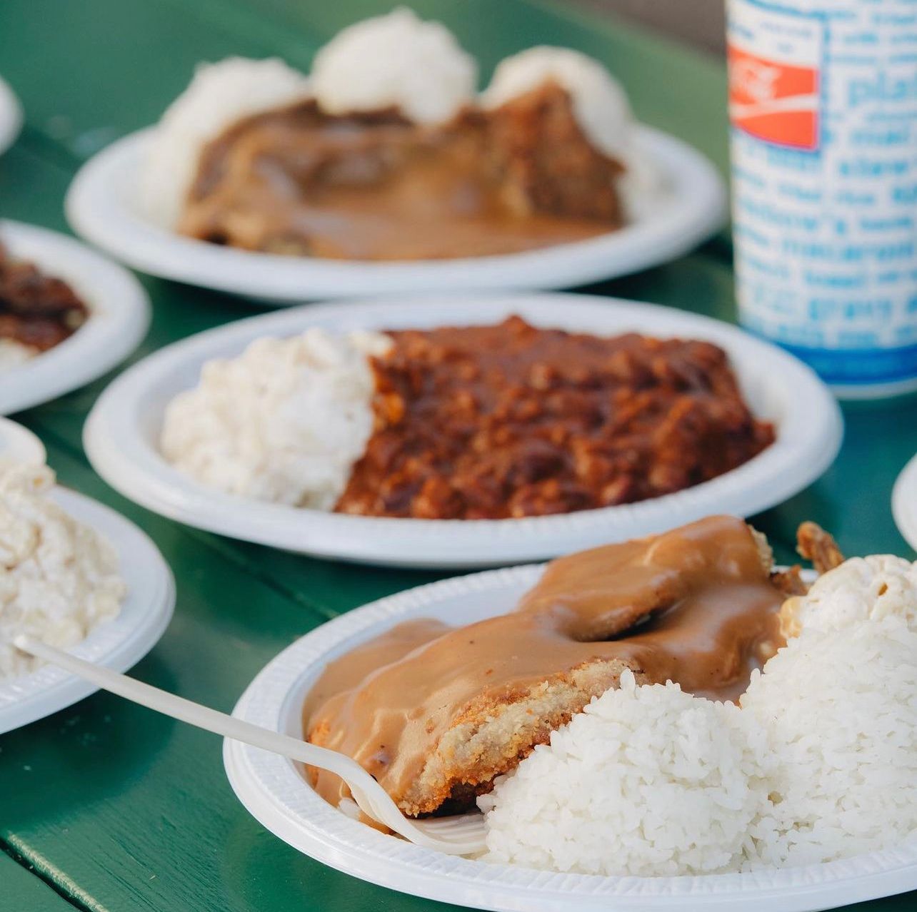 Plates of food on a table with a can of diet coke in the background