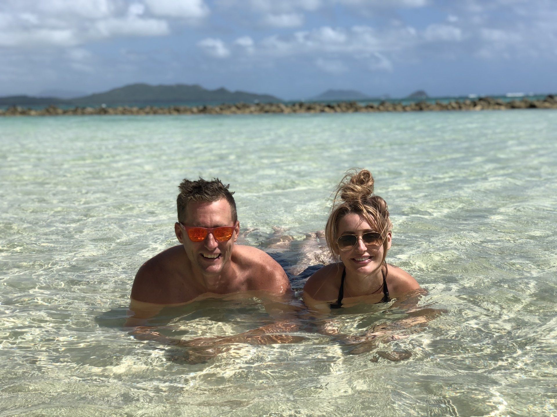 A man and a woman are laying in the water.