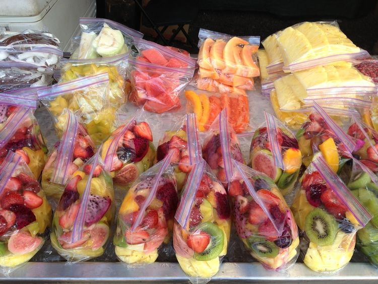 A variety of fruits are in plastic bags on a table.