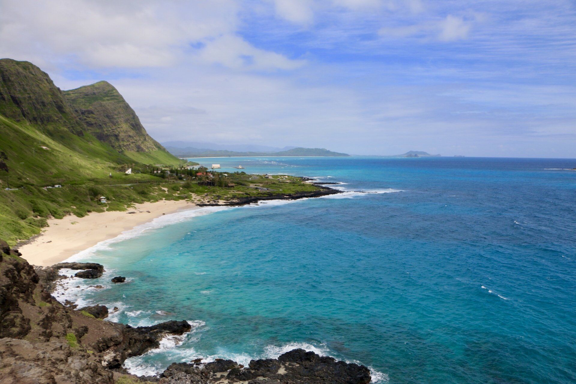 A view of a beach from a cliff overlooking the ocean.