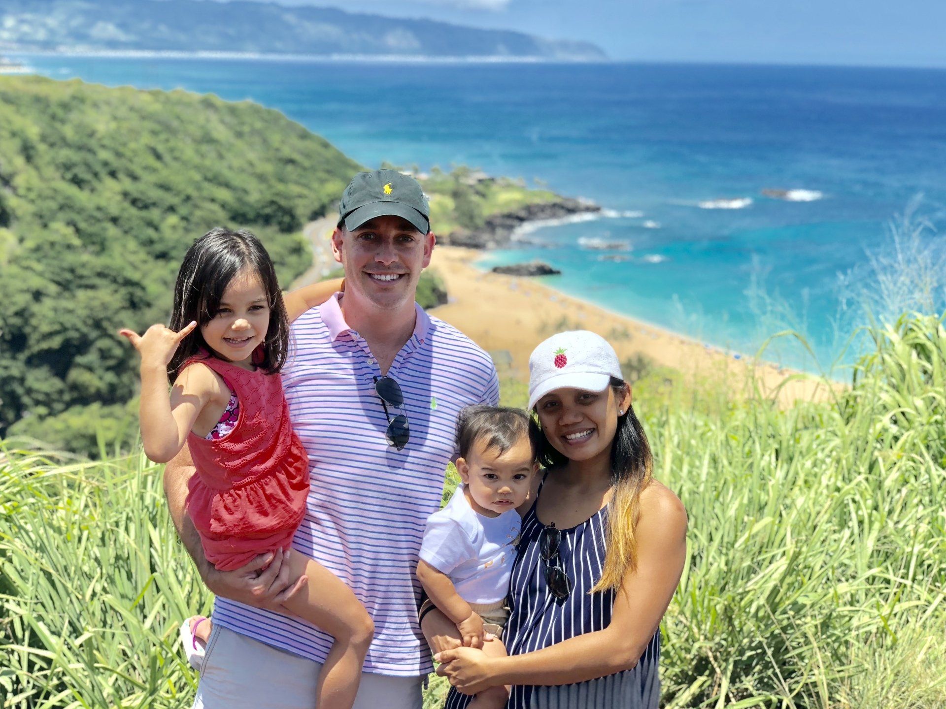 A family is posing for a picture in front of the ocean.