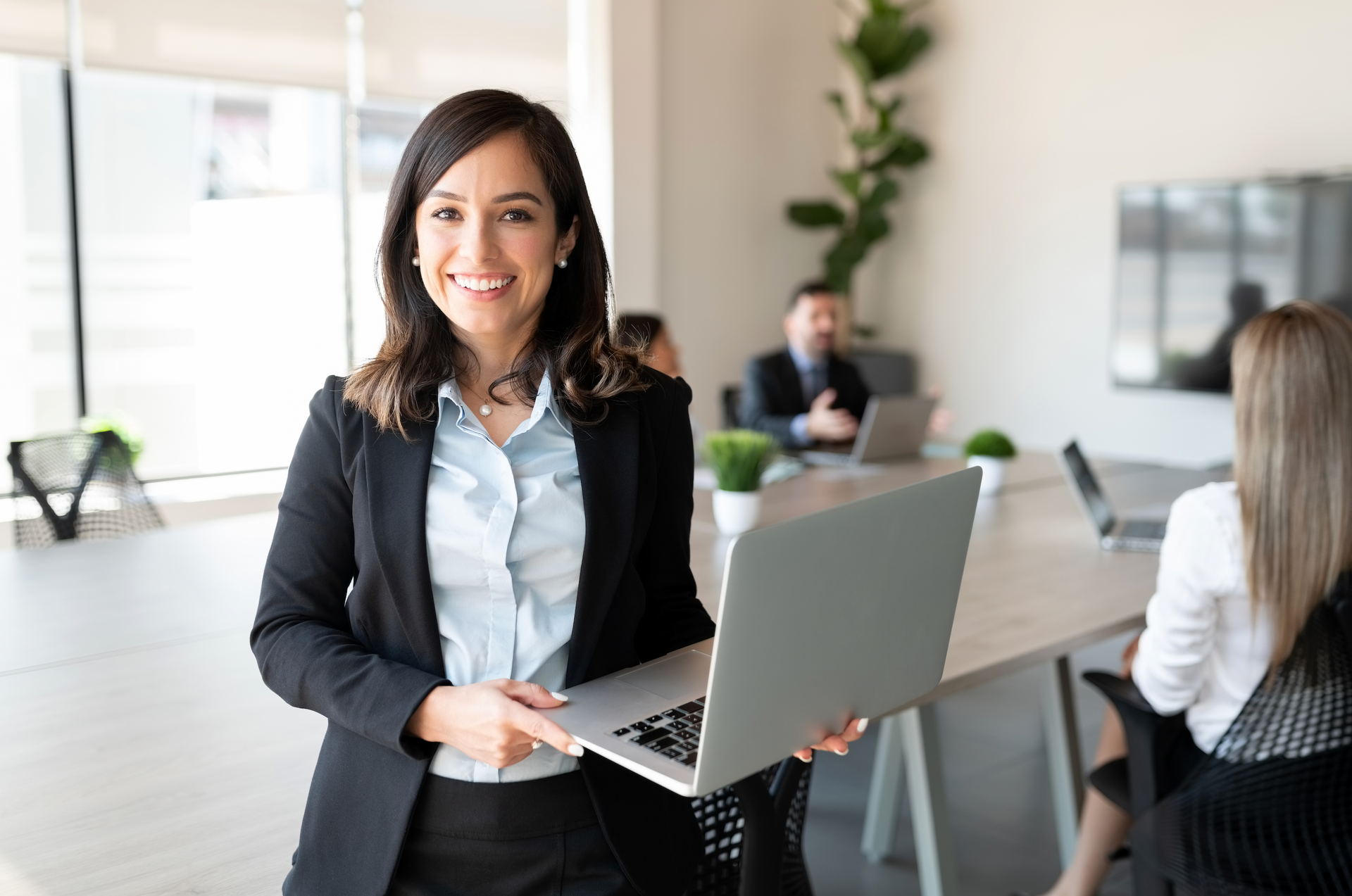 A woman is holding a laptop computer in an office.