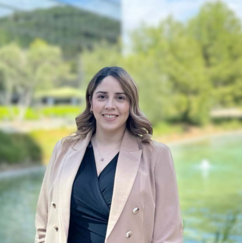 A woman in a pink jacket and black dress is posing for a picture.