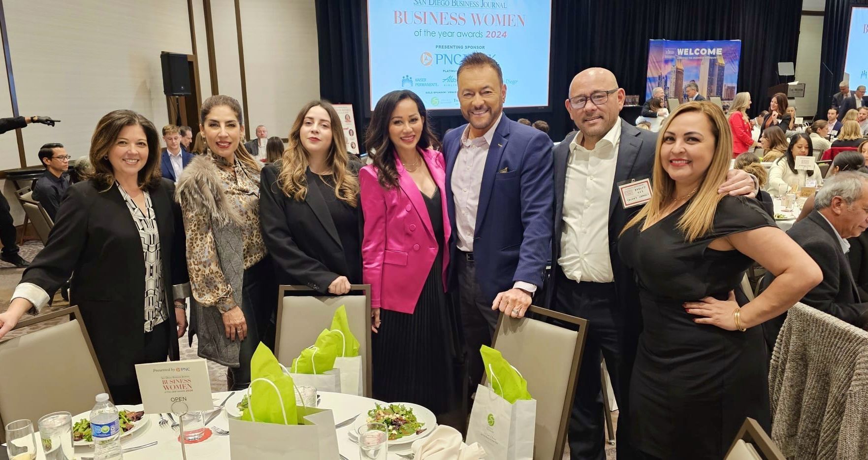 A group of people are posing for a picture at a table at a conference.
