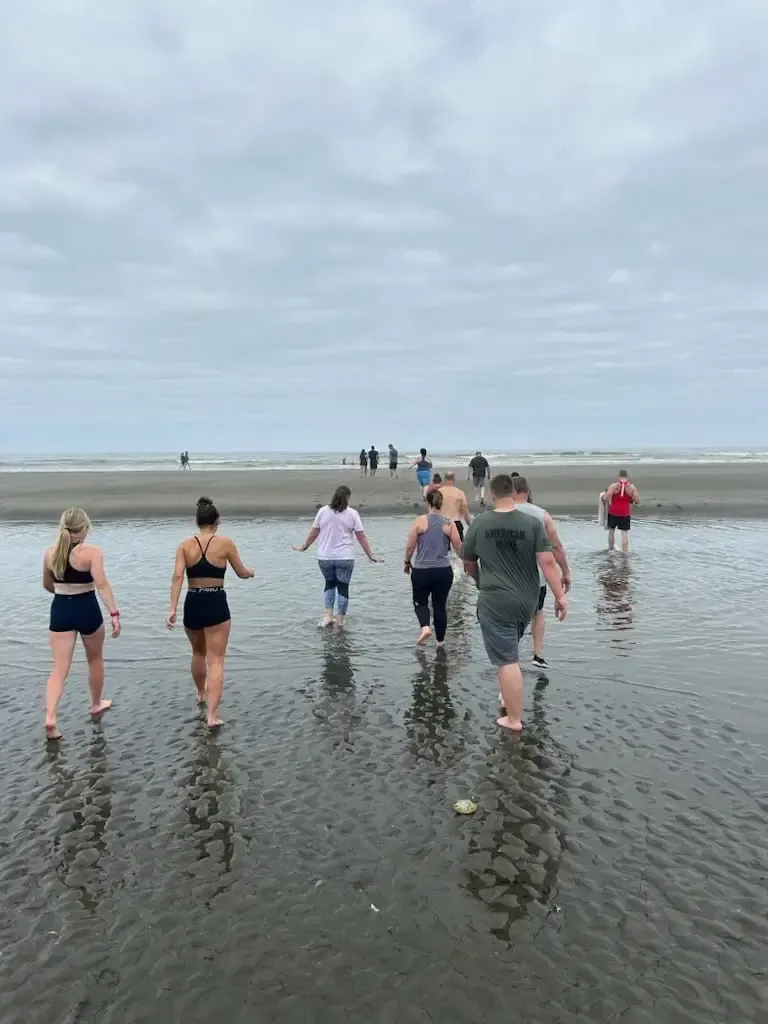 A group of people are walking on a beach in the water.