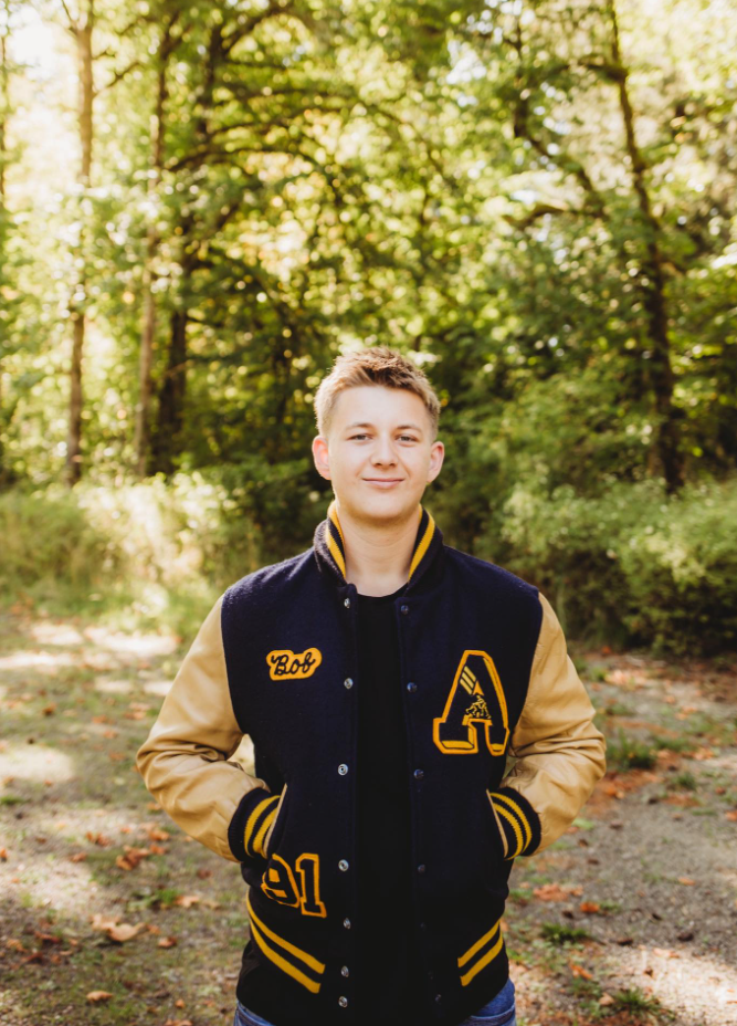 A young boy is smiling for the camera while wearing a lanyard around his neck.
