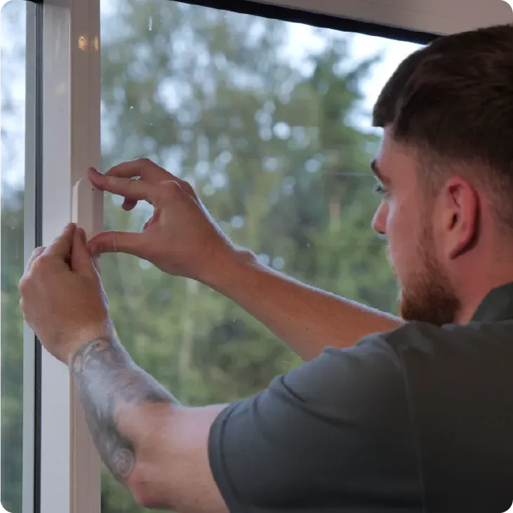Man installing a window. He is holding a piece of material, working next to a window frame.