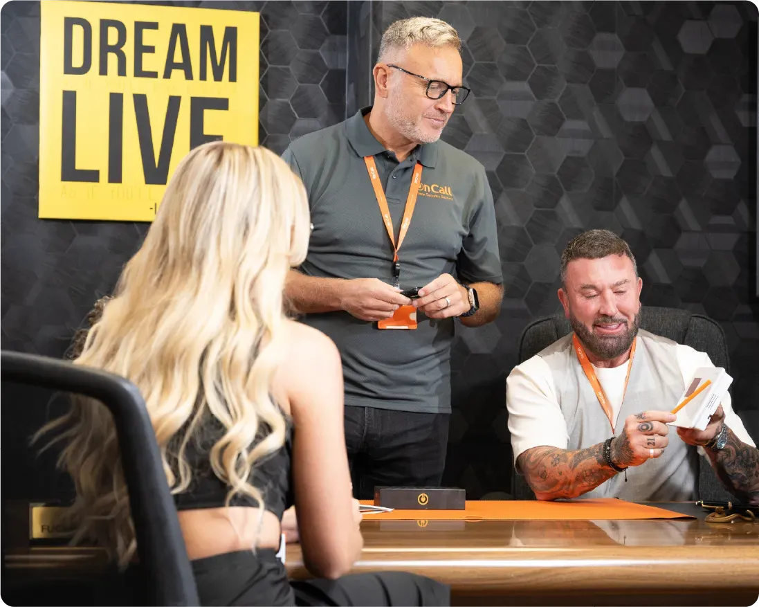 Three people at a table; blonde woman, man with tattoos, and man in glasses.