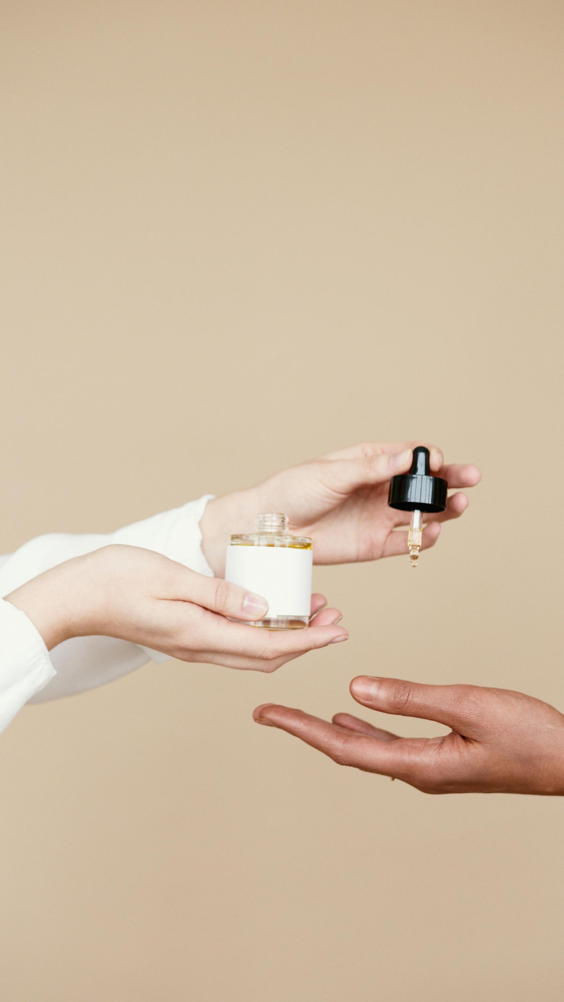 A woman is handing a bottle of perfume to another woman.