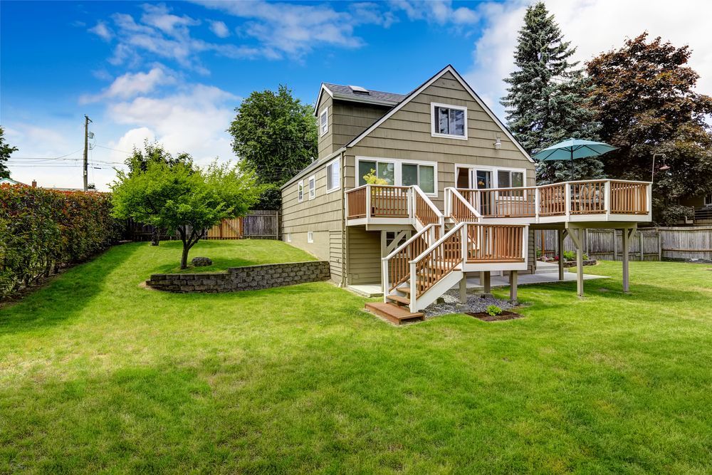 The backyard of a house with a large deck and stairs.