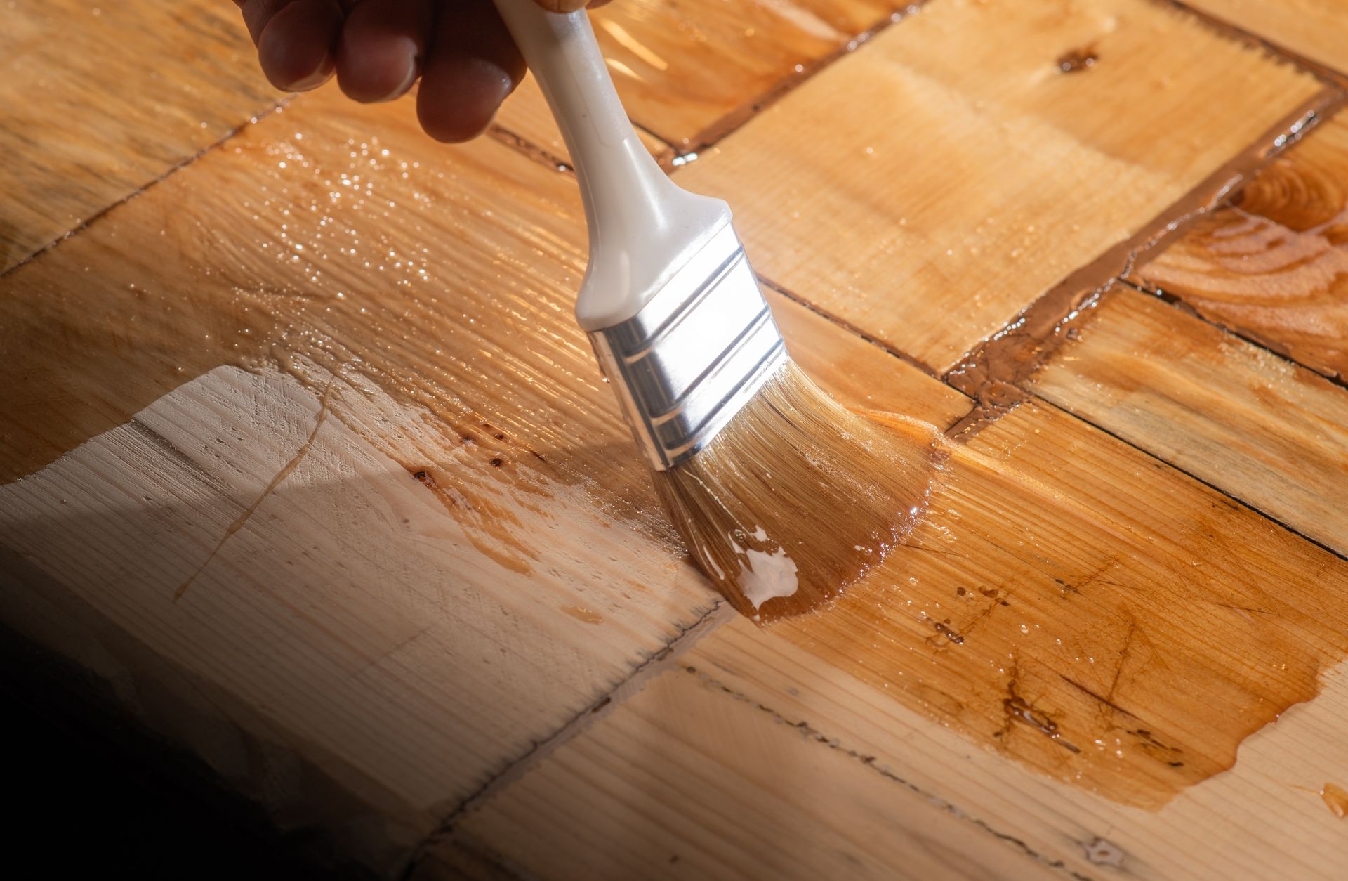 A person is painting a piece of wood with a brush.