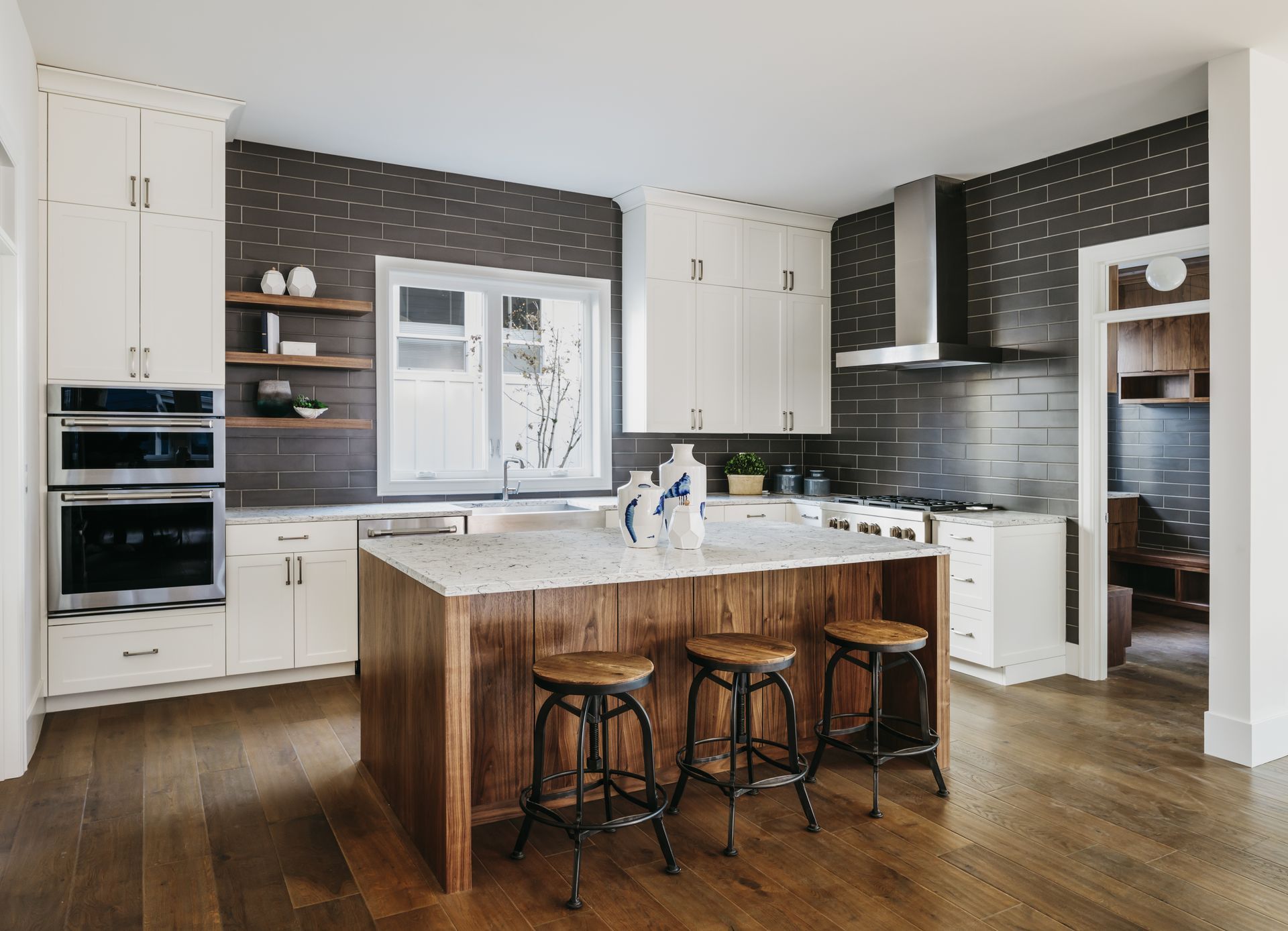 A kitchen with white cabinets , stainless steel appliances , a large island and stools.