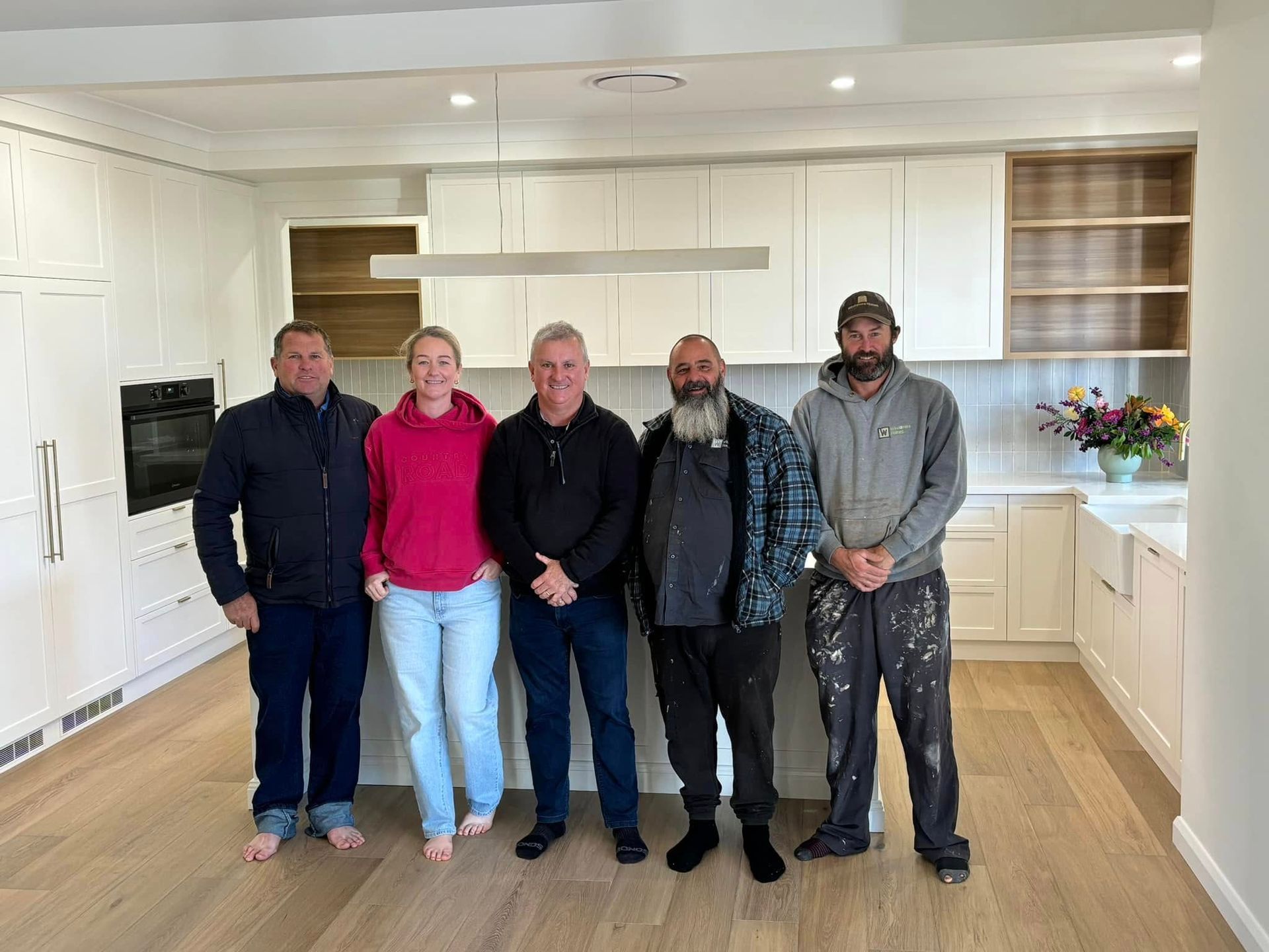 A group of people are posing for a picture in a kitchen. — Windamere Homes in Highfields, QLD