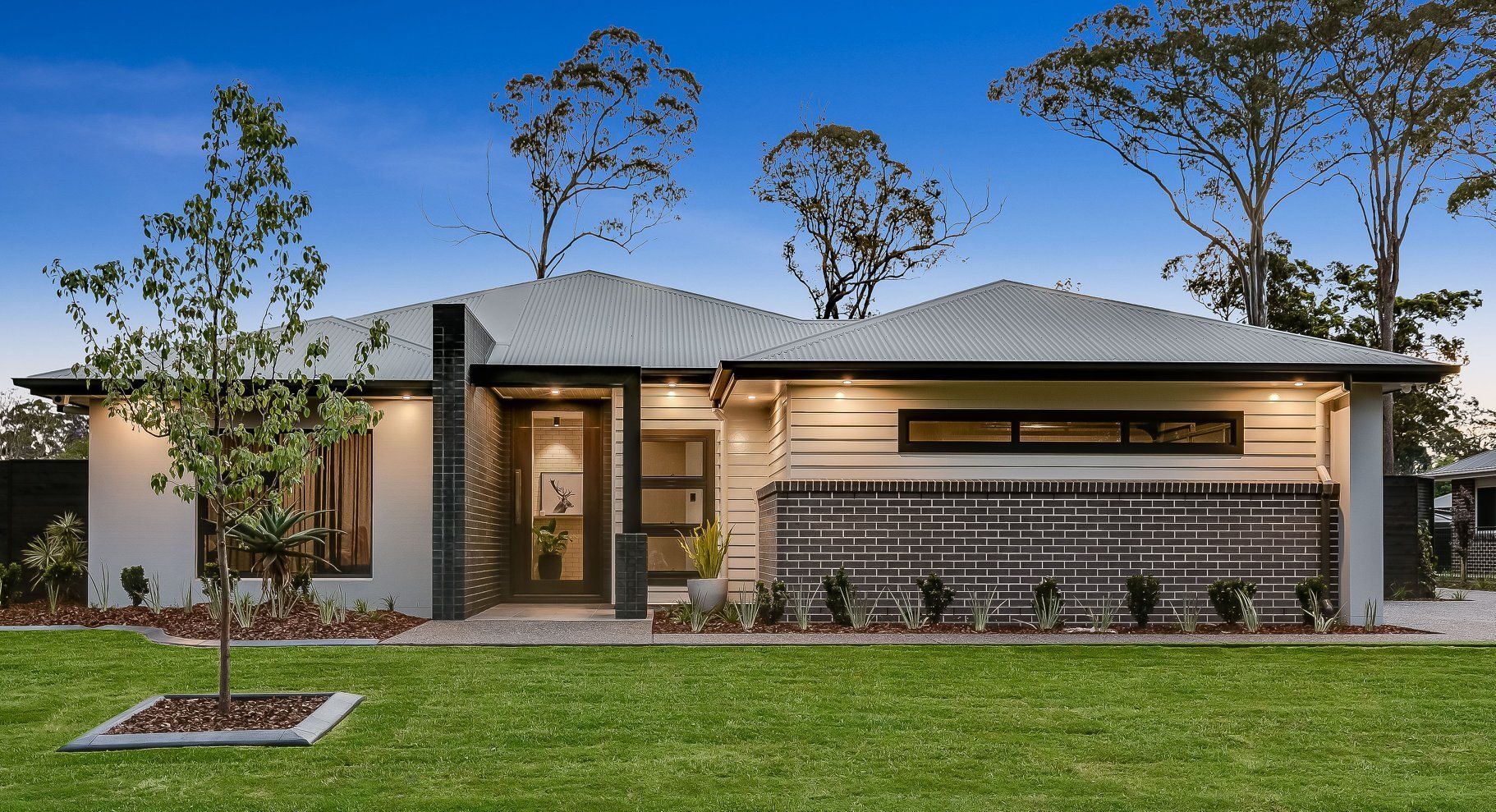 A modern house with a white roof is sitting on top of a lush green lawn. — Windamere Homes in Highfields, QLD