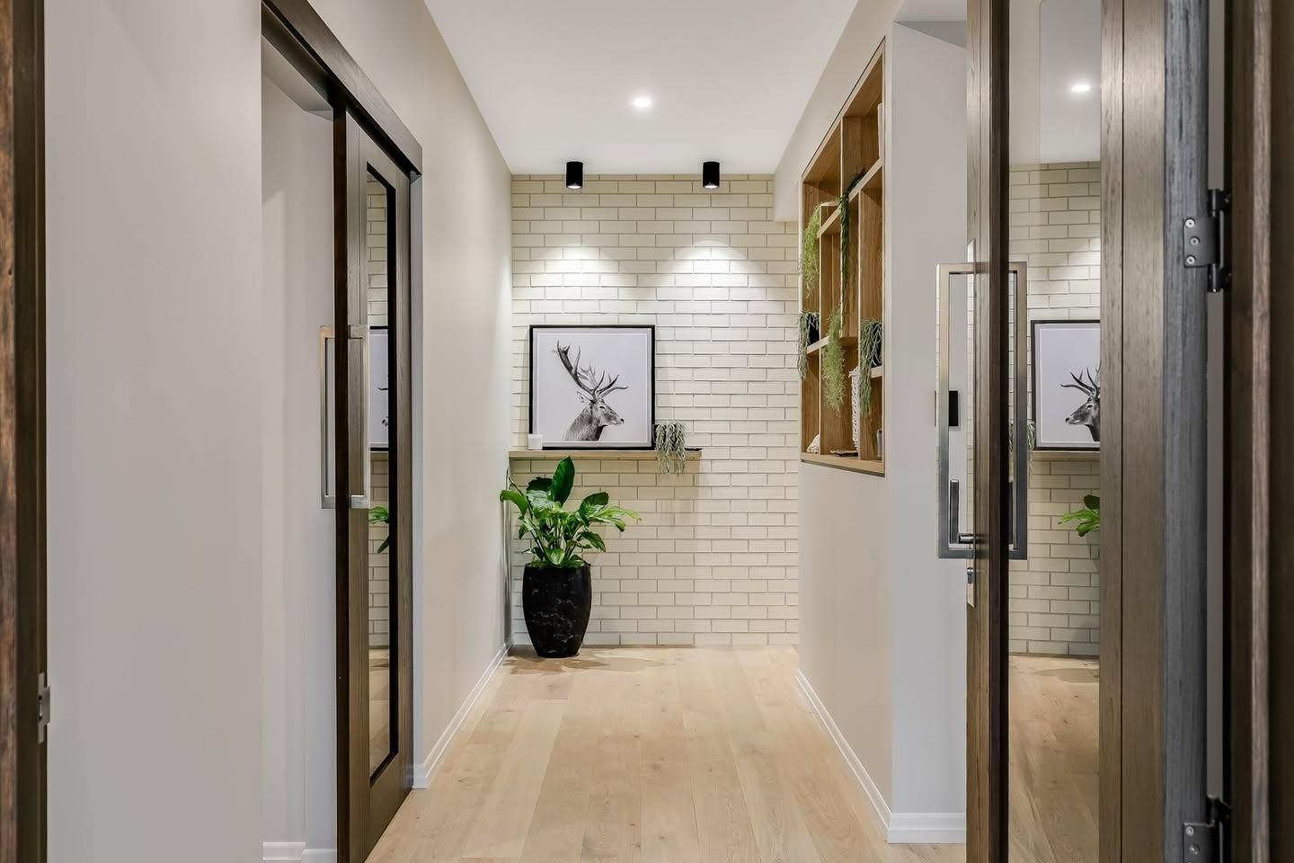 A Hallway With a Brick Wall , Wooden Floor , and Sliding Glass Doors — Windamere Homes in Highfields, QLD