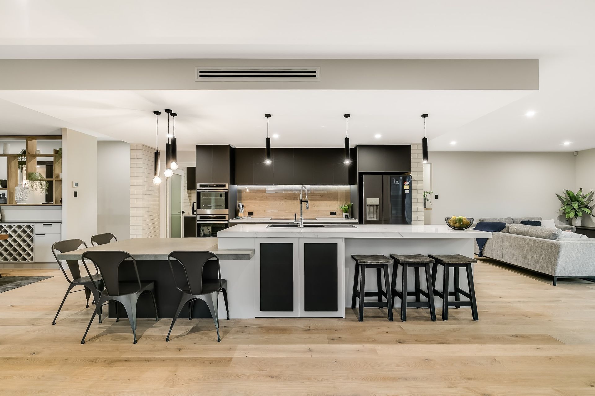 A kitchen with a large island and stools in it — Windamere Homes in Highfields, QLD