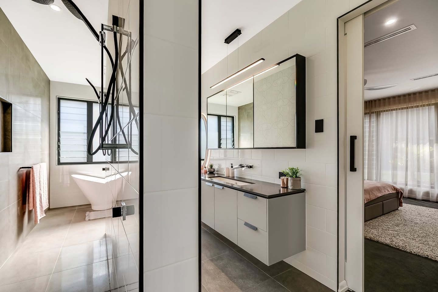 A bathroom with two sinks , a bathtub and a mirror. — Windamere Homes in Highfields, QLD